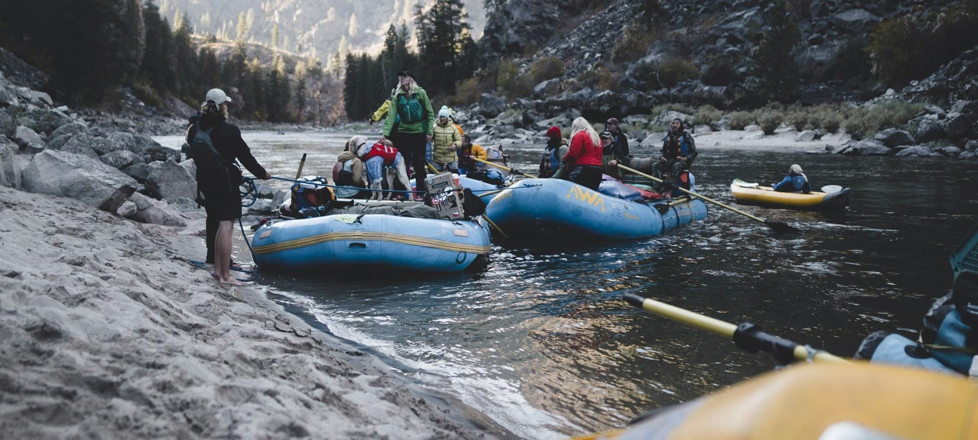Guides staging loaded rafts at a river put-in.